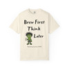 Brew First, Think Later – Bert’s Morning Motto Tee by Coo Coo’s Coffee in ivory, featuring frazzled Bert the gecko holding coffee.