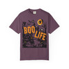 “Light green tee featuring haunted scene with jack-o’-lanterns, bats, witch, and orange text ‘Boo Life,’ Boo Life Tee by Coo Coo’s Coffee.”