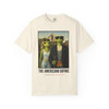 The Americano Gothic coffee tee — two geckos posed as the couple from Grant Wood's American Gothic in front of a white gothic-window farmhouse; Bert in sunglasses holding a pitchfork, Gertie in pearls beside him, with "The Americano Gothic" and a red Florida Brew Crew line beneath — Coo Coo's Coffee Brew Good Vibes garment-dyed Comfort Colors art parody tee.