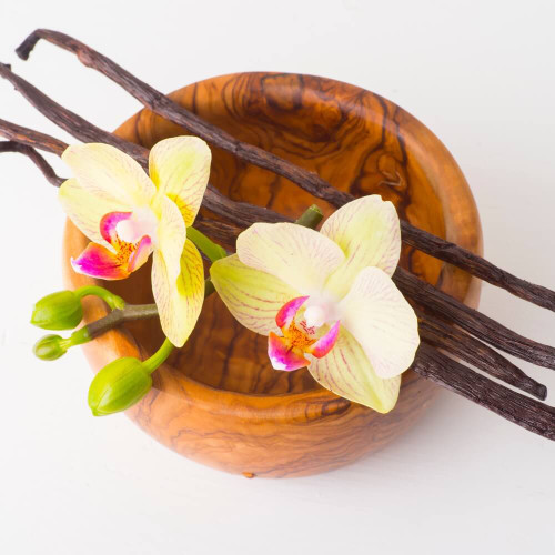 Vanilla beans and yellow orchid flowers in a wooden bowl, inspiration for Vanilla Bean wax melt scent
