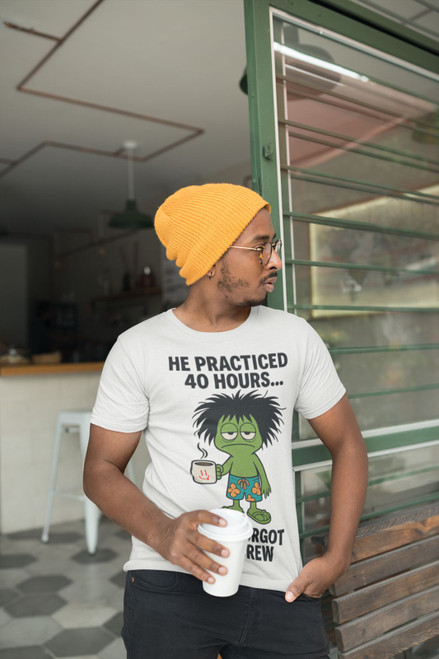 "Man wearing Practice Makes Exhausted – Frazzled Bert Tee by Coo Coo’s Coffee in grey, holding a coffee cup at a café. Funny coffee t-shirt with frazzled gecko Bert graphic, perfect for relaxed mornings and espresso fans."