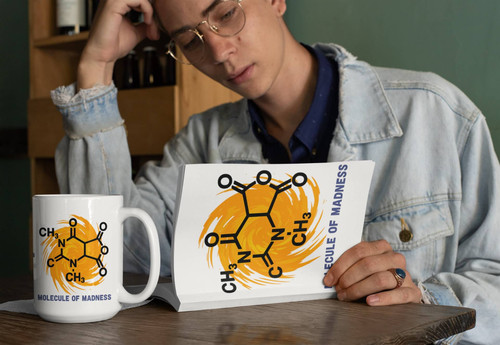 Person reading a matching Molecule of Madness print while a Caffeine Cyclone coffee mug rests beside the book