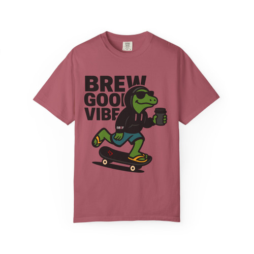 “Crimson red tee featuring Bert the gecko skating with hot coffee cup, bold lettering ‘Brew Good Vibes,’ Gecko Skate Crew Tee by Coo Coo’s Coffee.”