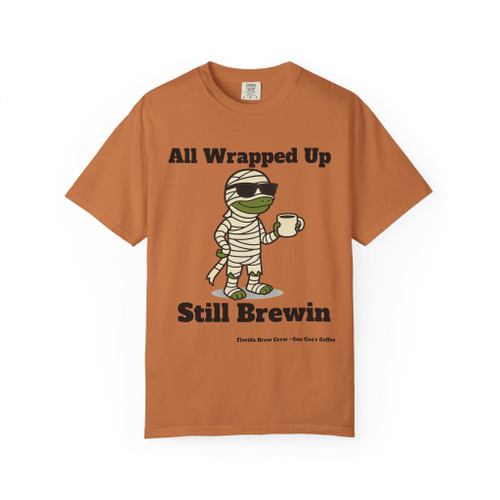 All Wrapped Up Still Brewin Halloween tee - mummy Bert the gecko wrapped in bandages with sunglasses holding coffee mug - front print on burnt orange ring-spun cotton by Coo Coos Coffee Florida Brew Crew