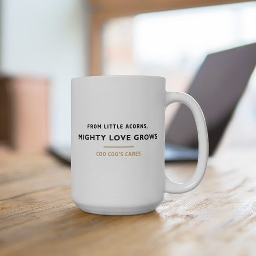 Our gold-ribbon squirrel on one side, from little acorns, mighty love grows on the other — a big 15oz cup for slow mornings and the people who need a small, steady reminder that love keeps growing. Cup on desk handle right