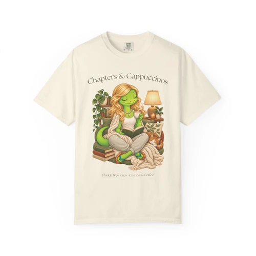 Chapters & Cappuccinos coffee t-shirt — Gertie reading with a cappuccino, cozy book-lover art printed on the front, ivory