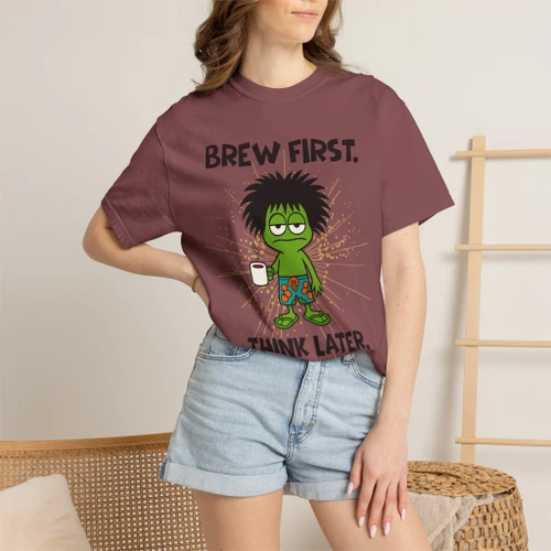 Close-up of the gecko Bert brewing, “brew first, think later” graphic print on the Brew First, Think Later t-shirt, brick