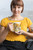 Woman in a yellow top showing the Paw-sitive Mornings Dog Bone Mug by Coo Coo’s Coffee, a cheerful coffee mug for dog and cat lovers alike.