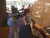 Person sipping Wake the Art Up mug behind café glass — moody studio-coffee vibe — Coo Coo’s Coffee