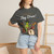 Close-up of the cartoon gecko Bert drumming, caffeine-and-music graphic print on the Geckos Don’t Sleep, They Play Drums t-shirt, pepper