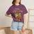Close-up of the cartoon gecko Bert playing cowbell on a Havana coffee tour graphic print on the More Coffee, More Cowbell t-shirt, berry