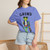 Close-up of the skateboarding gecko Bert grinding a rail with coffee graphic print on the Grind t-shirt, flo blue female