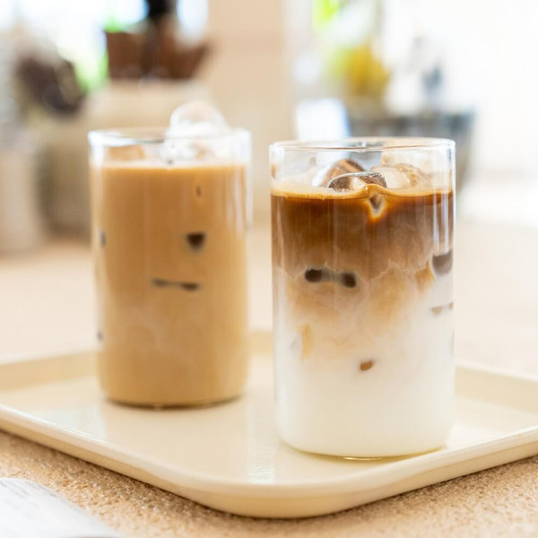 "Two iced lattes with layers of milk and espresso beside Graham Cracker Latte Wax Melt, highlighting the creamy almond, graham cracker, and butter rum scent inspiration."
