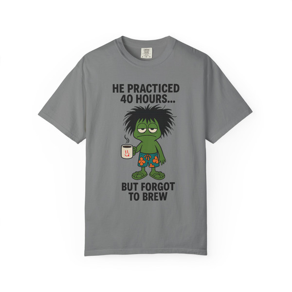 Practice Makes Exhausted – Frazzled Bert Tee in Grey by Coo Coo’s Coffee. Coffee humor shirt with frazzled Bert the gecko clutching a mug, ideal for coffee addicts and espresso enthusiasts who know exhaustion without a brew. Soft comfort fit tee for everyday wear.