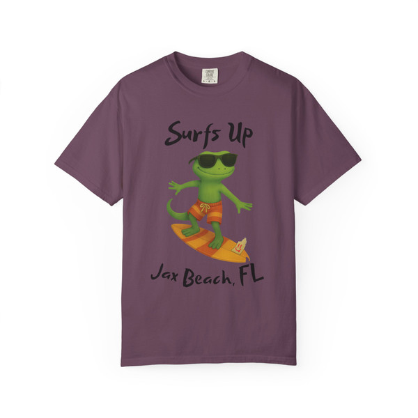 Berry purple short-sleeve tee with Bert the gecko surfing graphic, featuring text “Surfs Up – Jax Beach, FL,” part of Bert’s Surf Club collection by Coo Coo’s Coffee.