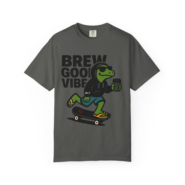 “Pepper grey tee showing Bert the gecko in hoodie and shades skating with coffee cup, slogan ‘Brew Good Vibes,’ Gecko Skate Crew Tee by Coo Coo’s Coffee.”