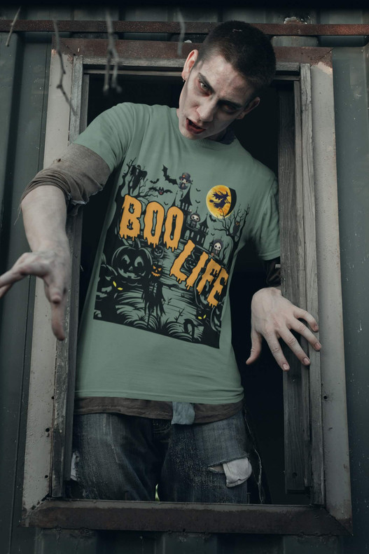 Zombie character leaning out of a doorway wearing a light green “Boo Life” Halloween T-shirt with spooky pumpkin and haunted house design – creepy horror fashion shot by Coo Coo’s Coffee.