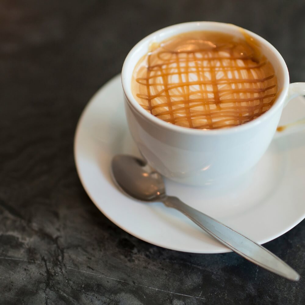 Caramel latte in a white cup with a spoon