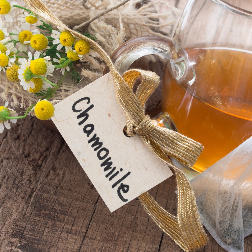 Chamomile tea in a glass cup with chamomile flowers on a table