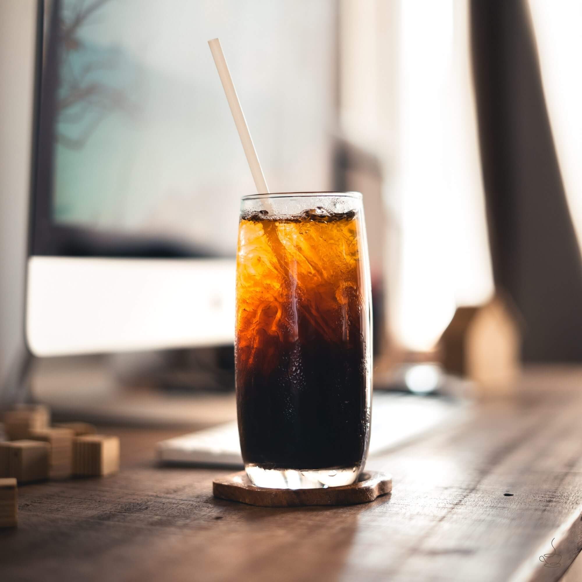 Glass of iced coffee with milk swirling over ice