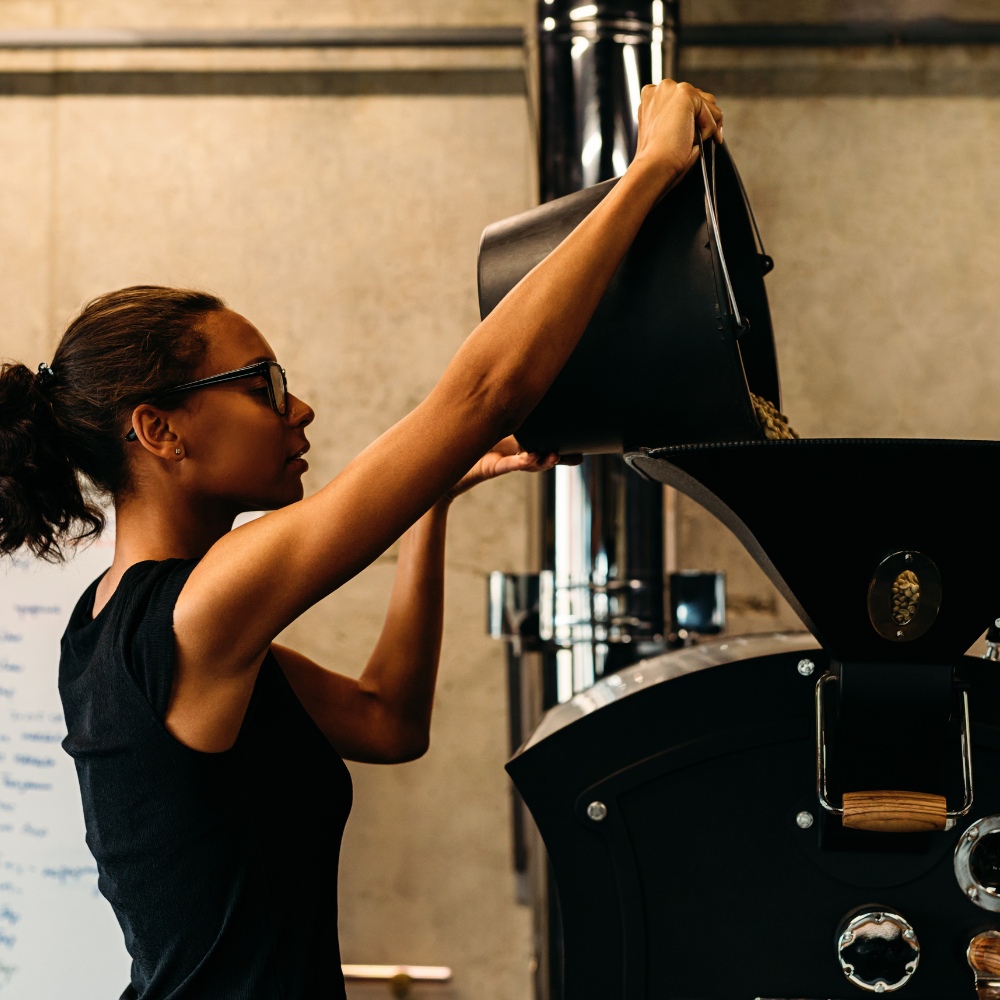 Female roast master charging a coffee roaster