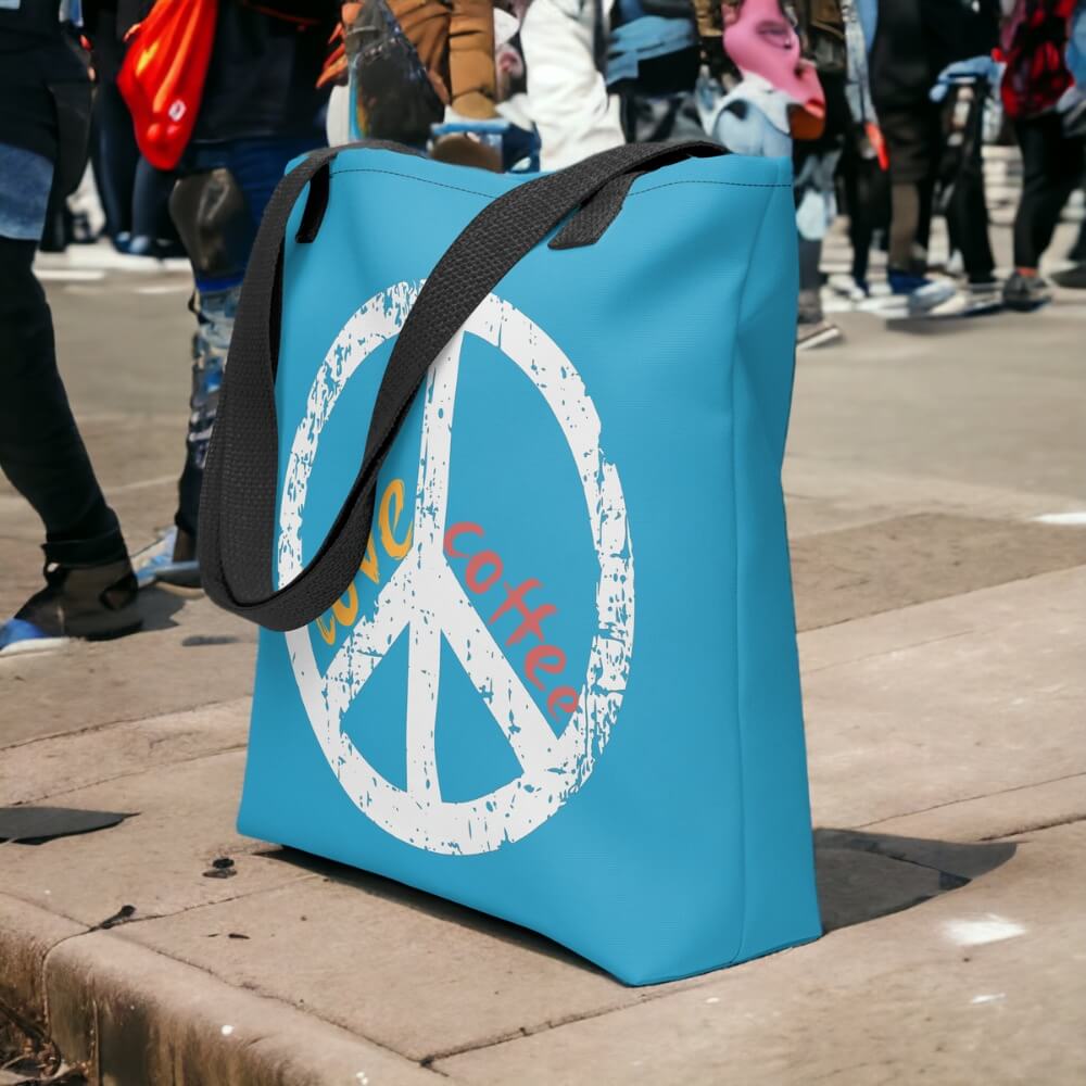 Blue Peace Love Coffee tote bag on crowded sidewalk.