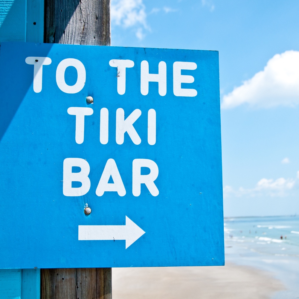 To the tikt bar with arrow blue sign at the beach