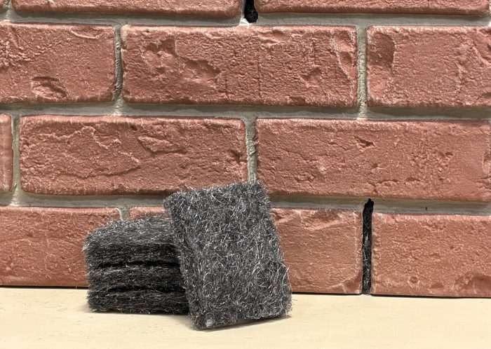 Xcluder Weep Fill pieces in front of a a brick will with weep holes.