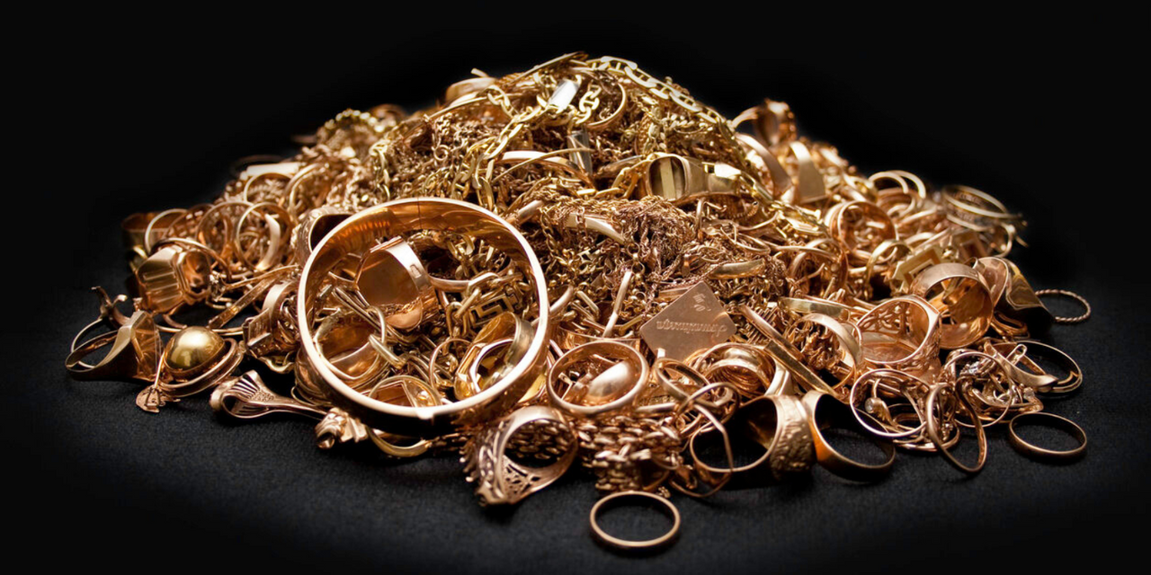 A hand holding a pile of random scrap gold dripping from the hand. 
