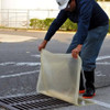Clear drain seal being positioned over a storm drain, highlighting its 18” x 18” size and easy application for environmental protection.
