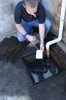 Person placing an Archaea miniboom into a storm drain.