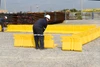 Workers assembling yellow containment wall panels on a gravel lot.