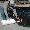 Person installing a self bailer under a container to manage liquid drainage effectively.