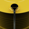 Close-up of thick black liquid pouring from a yellow drum, highlighting fluid viscosity and flow.