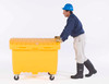 A man wearing a blue hard hat and gloves pushing a yellow utility box equipped with wheels, demonstrating its portability.