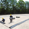 Workers carefully installing a waterproof liner on a flat surface, ensuring long-lasting protection.