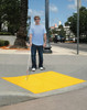 Person with a white cane standing on a yellow tactile ADA pad near a crosswalk. Person with a white cane standing on a yellow tactile ADA pad near a crosswalk.