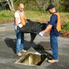 Two workers installing a catch basin near a jobsite for protection against outside elements that may enter the drain during construction.