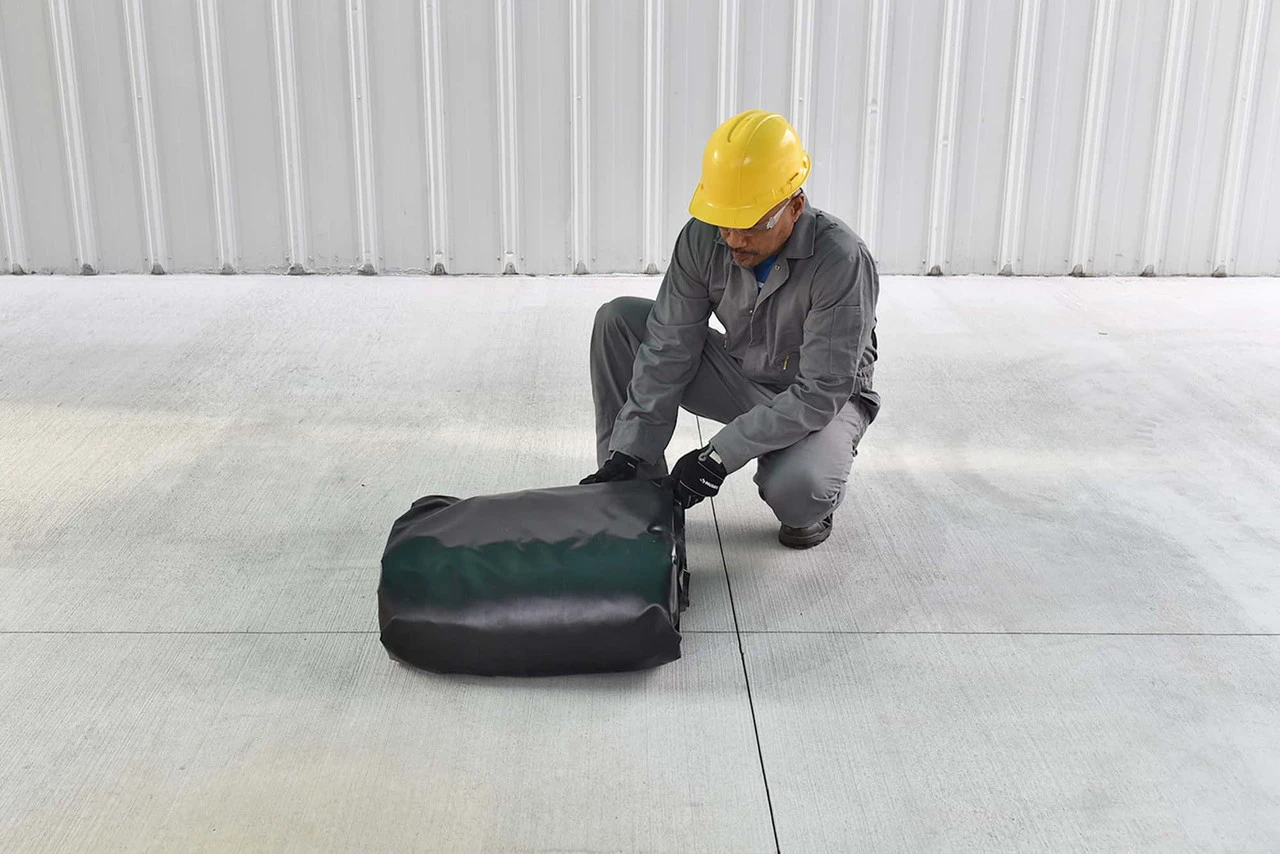 Folded berm with worker - Worker preparing the folded containment berm for transport or storage.