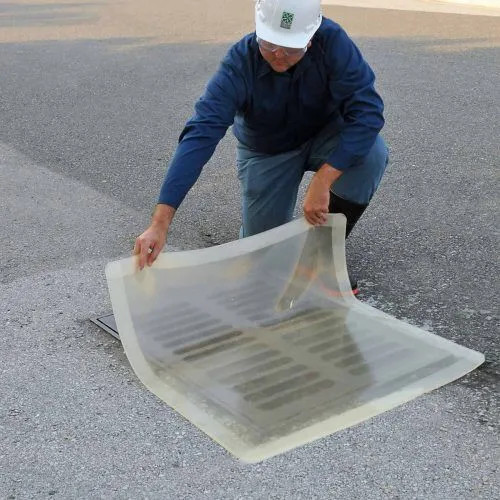 Worker placing a clear 18” x 18” drain seal over a drain, showcasing its flexibility and secure coverage for spill control.