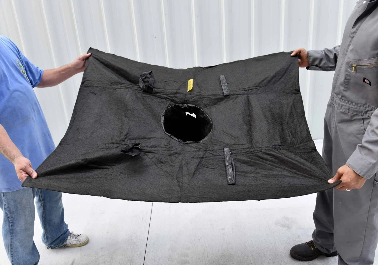 Standard storm drain being held up in a warehouse by two workers getting ready to install the basin for compliance.