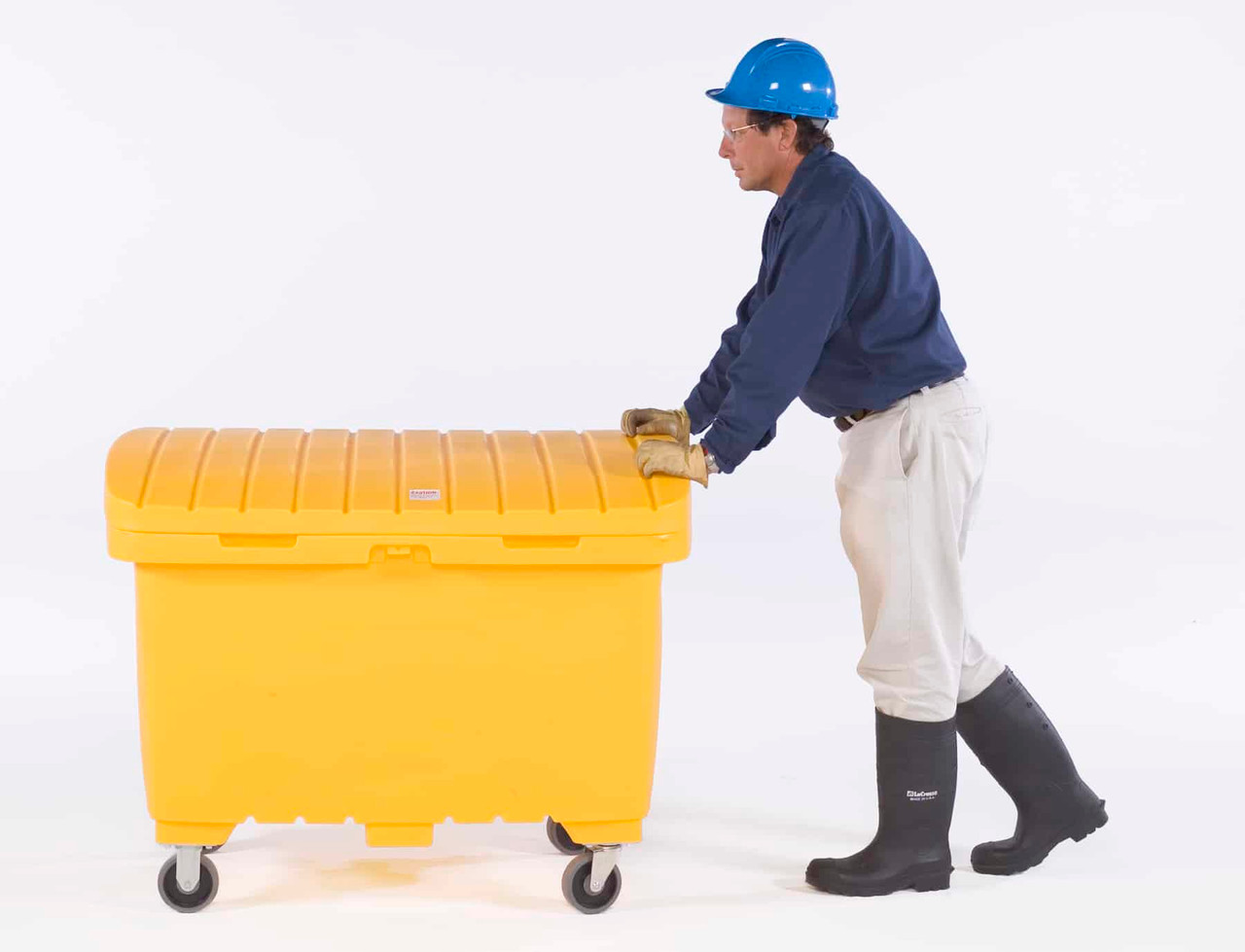 A man wearing a blue hard hat and gloves pushing a yellow utility box equipped with wheels, demonstrating its portability.