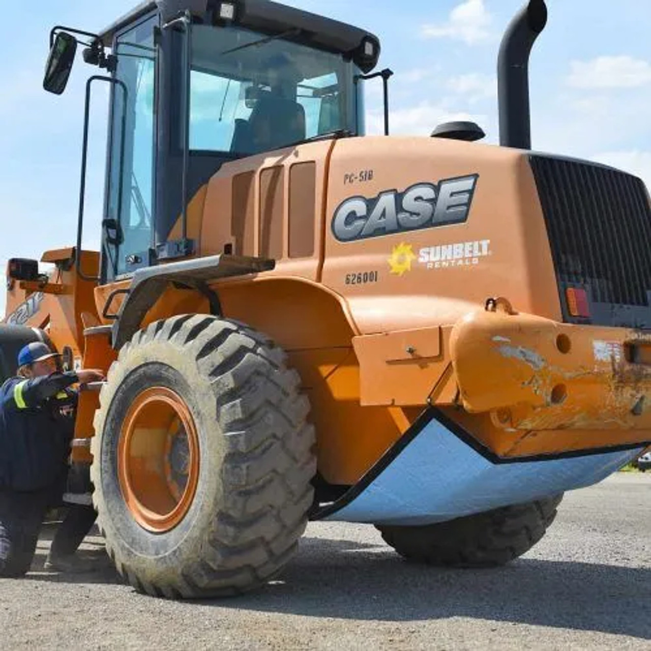 A worker securing a spill containment mat to the underside of an industrial vehicle, providing leak protection during operations.