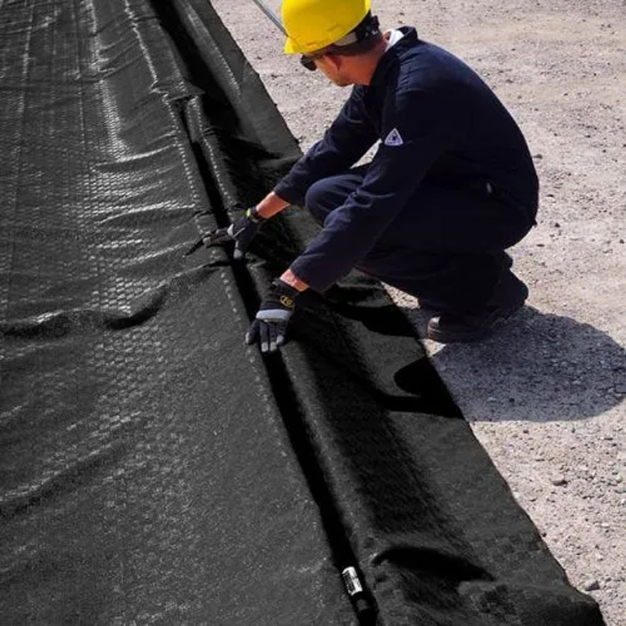 Worker securing a modular berm liner with a 2' x 2' corner section for a perfect fit and reliable industrial spill containment.