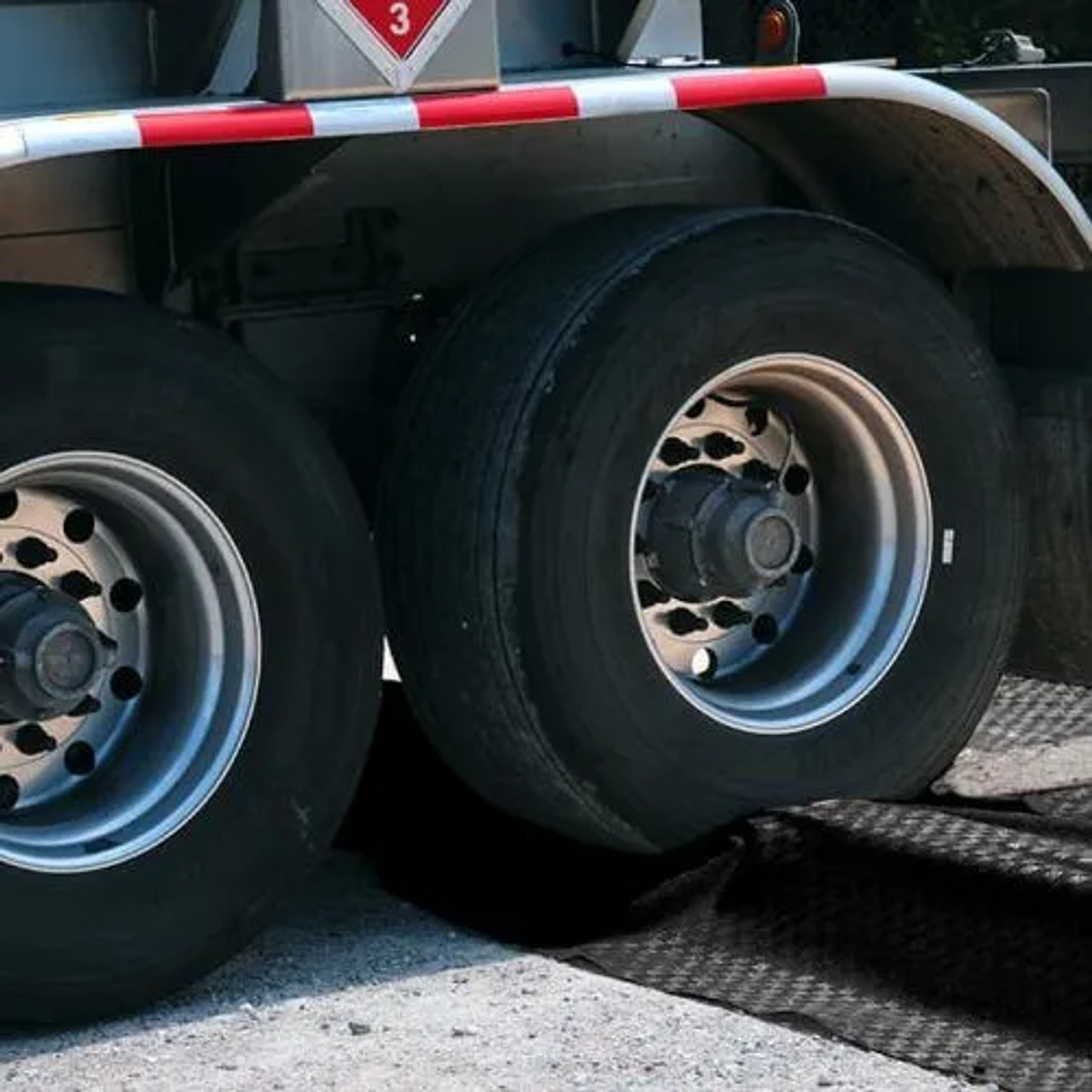 Close-up of truck wheels on a modular containment berm with a corner section, demonstrating durability and heavy-duty performance.