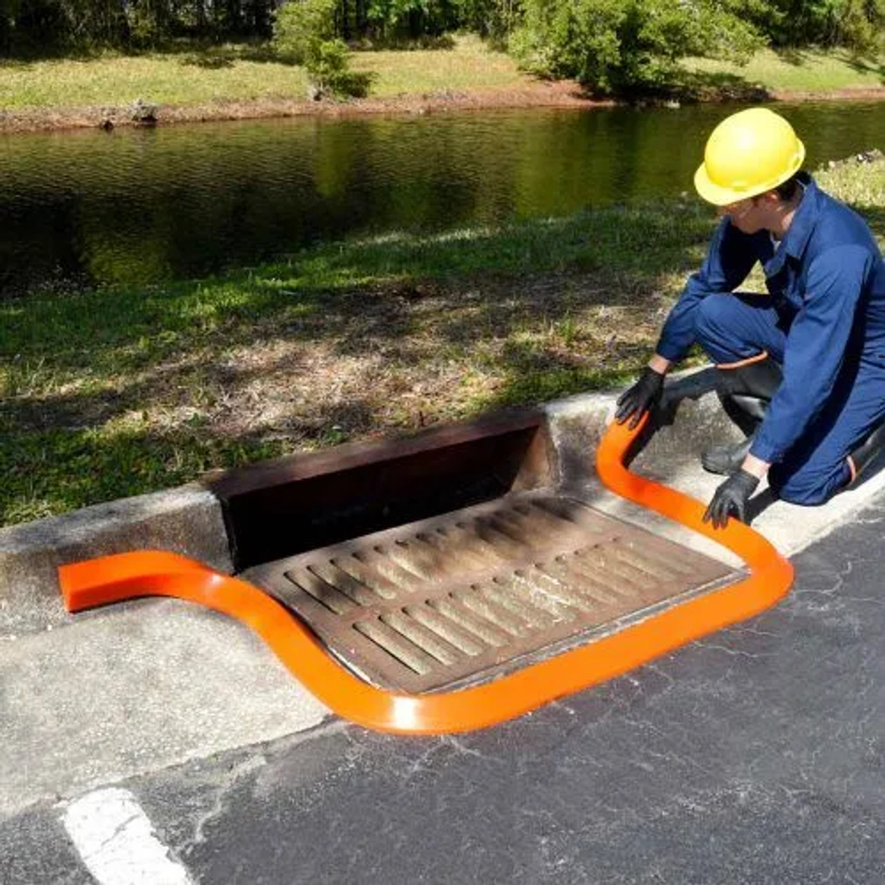 Worker using a Spill Berm Connector to securely join two orange spill berms for expanded containment.