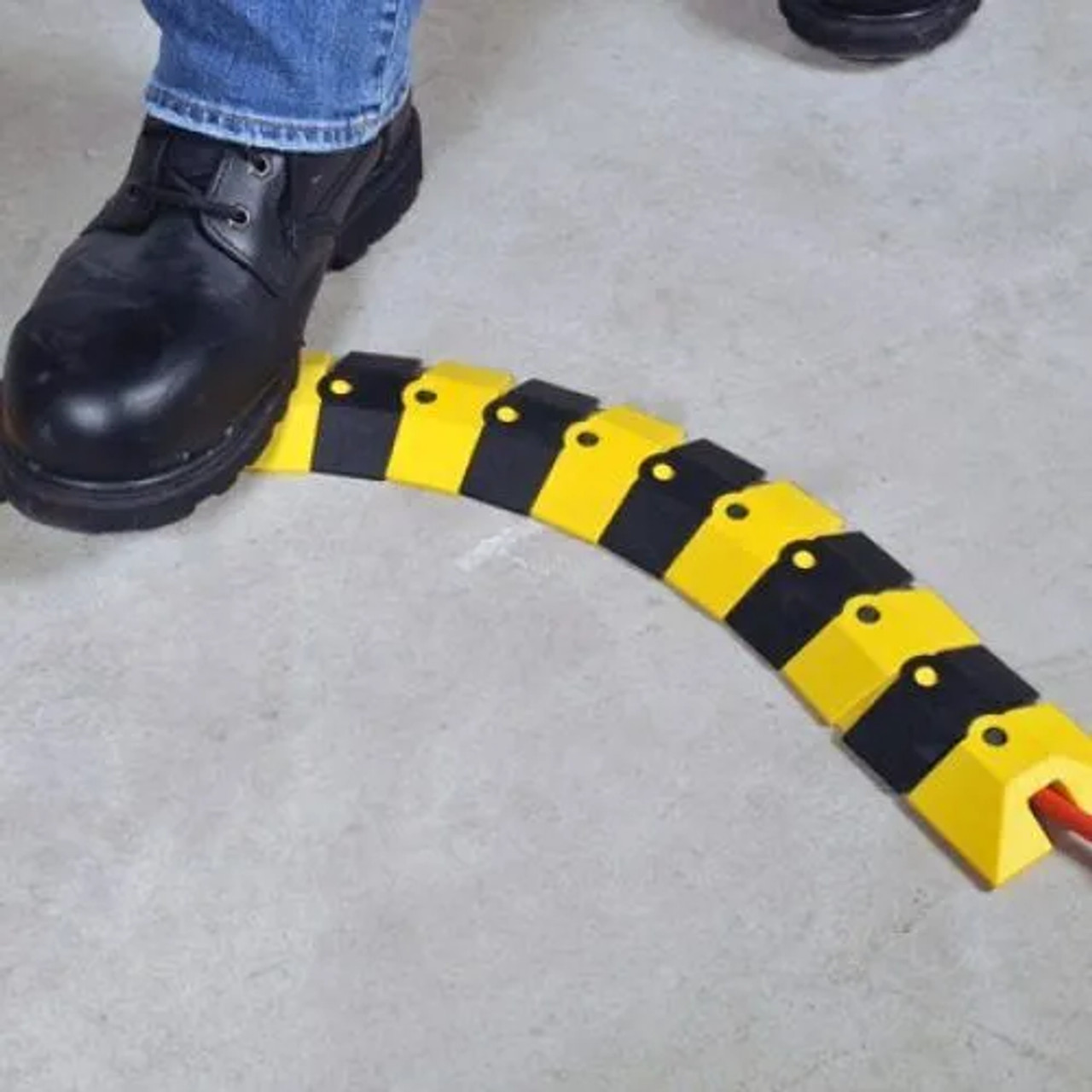 Worker stepping over a connected Sidewinder Extension, Medium, Black, demonstrating its functionality and trip-hazard reduction.