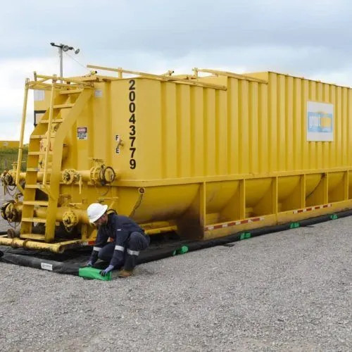 Yellow industrial storage container positioned near a foam wall spill containment berm for leak prevention.