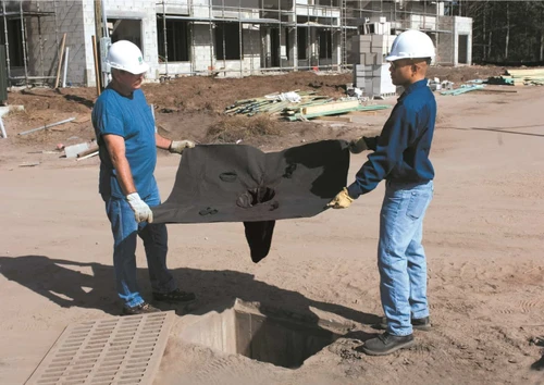 Two workers getting ready to install a drain guard to avoid compliance issues and keep pollutants out of their drains.