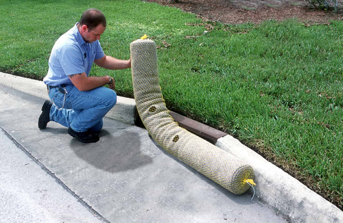 Worker positioning an Ultra-Gutter Guard in front of a curb inlet, ensuring proper placement for stormwater sediment and debris control.